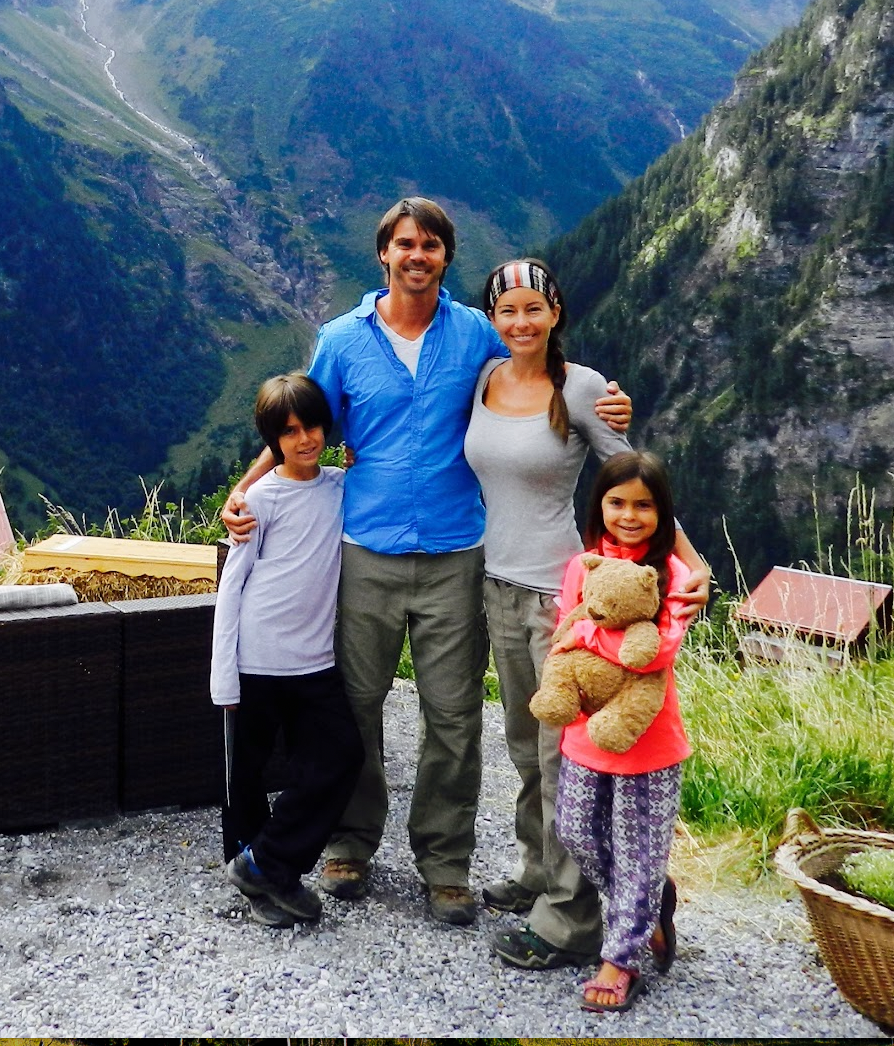 Young Zingg family starts their homeschool adventure.  Mom, dad, and two young kids stand in front of the Swiss mountains.